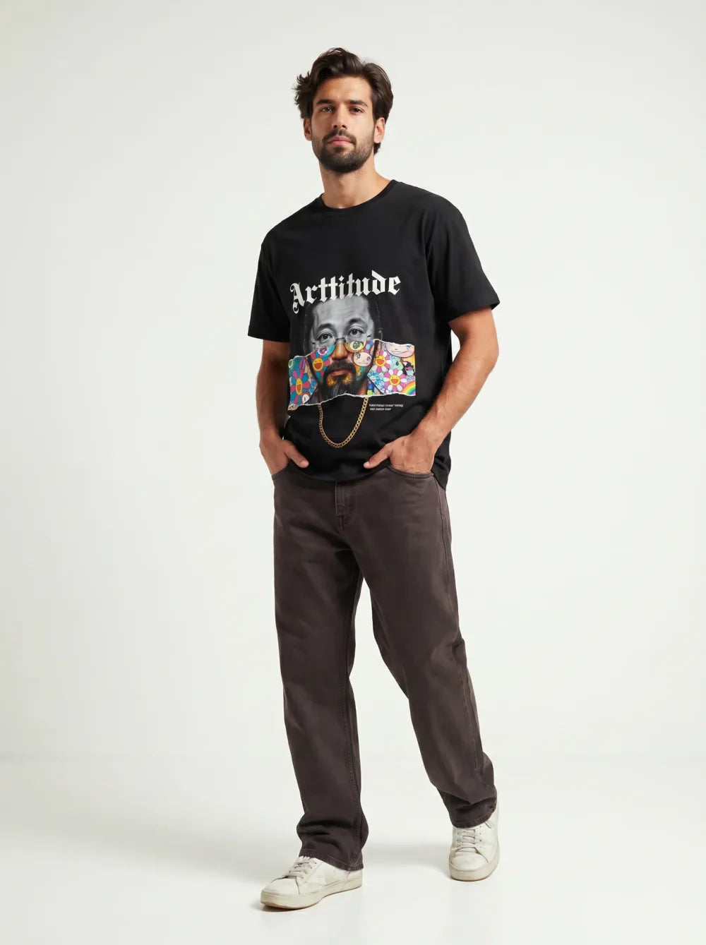 Black tee with a colour portrait print on a floral ground, brown trousers, tan sneakers, gold chain necklace