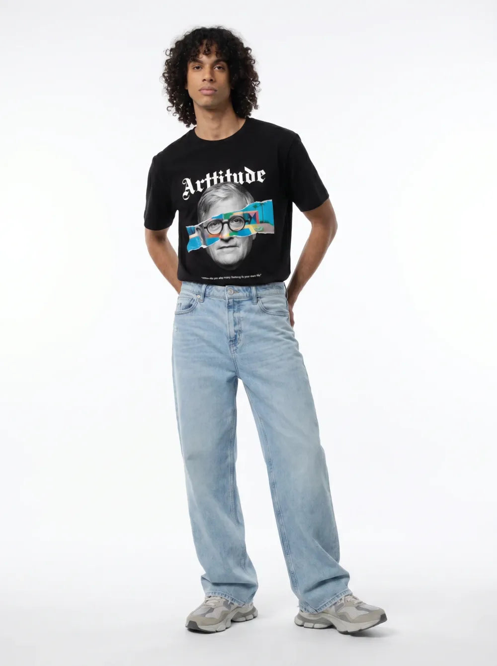 Black tee with a portrait print, colourful graphic band over the eyes, light-wash jeans, grey sneakers