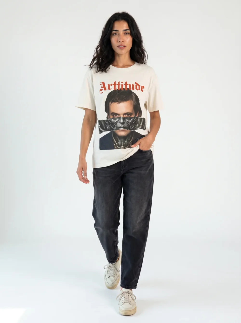Cream tee with a monochrome portrait print, metallic mask over the mouth, black wide jeans, cream sneakers